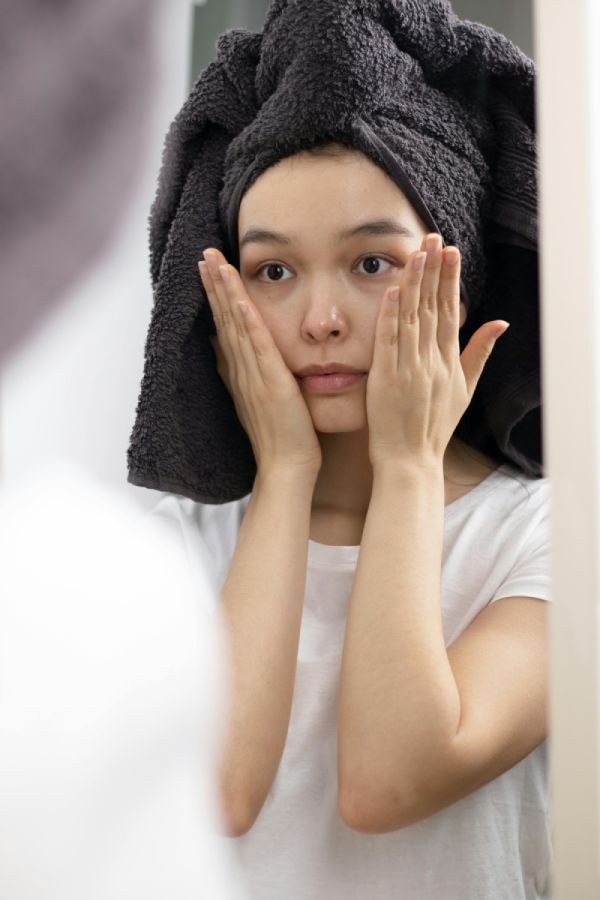mujer con toalla en la cabeza tocándose la cara