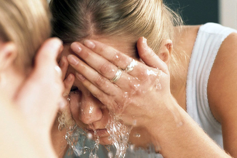 Chica lavándose la cara con agua fría. Foto de Mejor Con Salud.