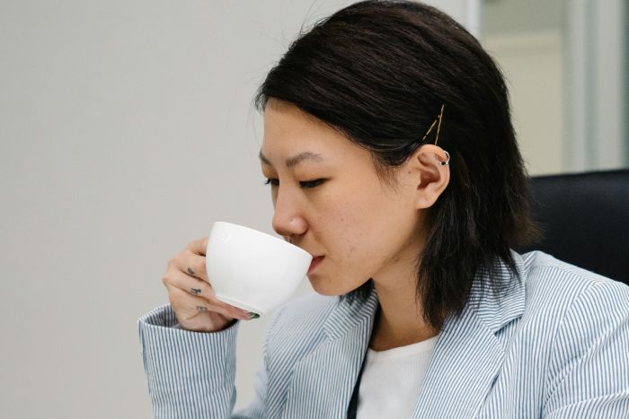 mujer con horquillas en el pelo tomando cafe