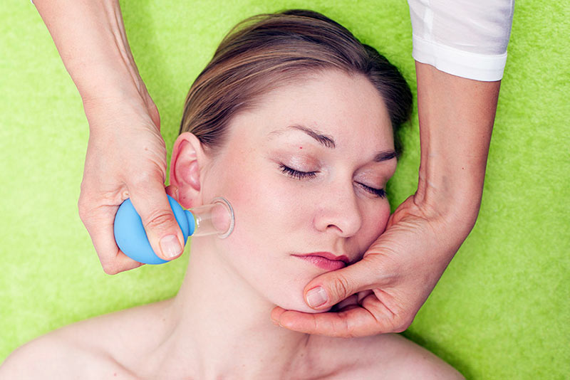 Mujer masajeándose el rostro con una ventosa facial. Foto de @Vacuum-therapy