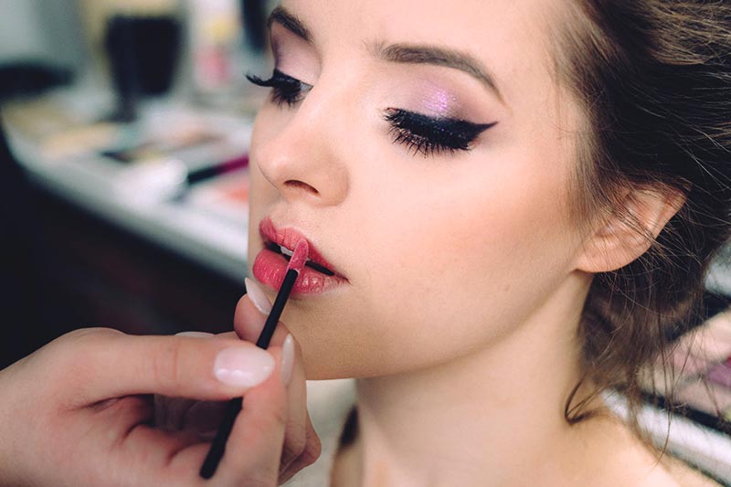 Chica de piel clara pintándose los labios con un tono favorecedor. Foto de Pexels