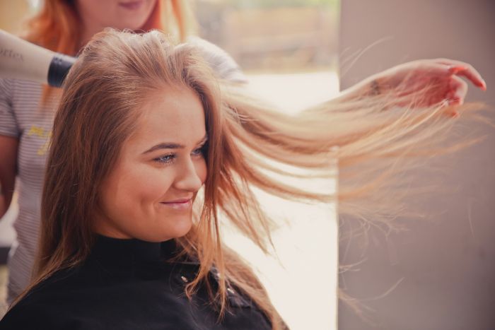 mujer en la peluquería secándose el pelo sonriente