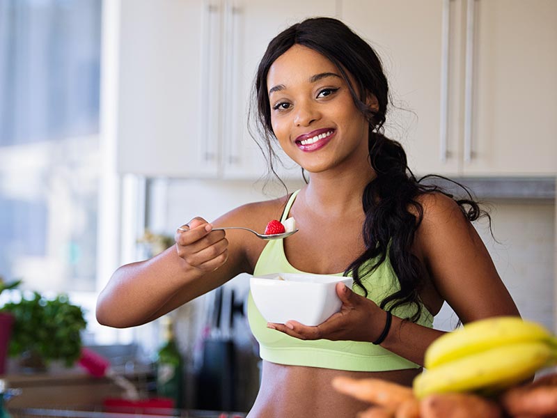 Mujer comiendo un bol de frutas.