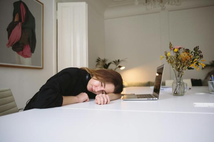 mujer dormida sobre mesa y delante del ordenador