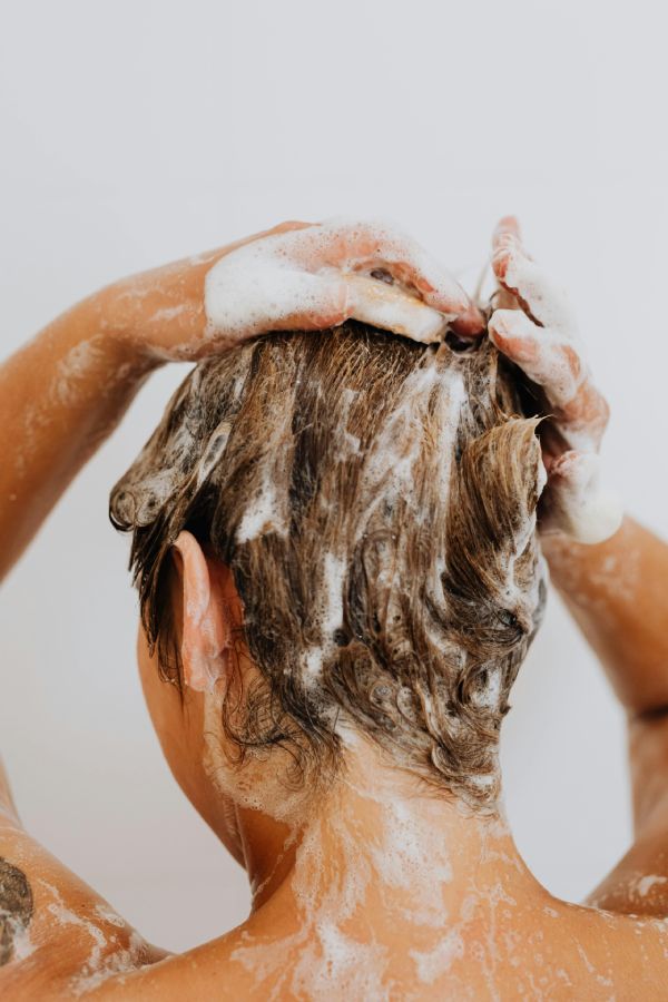 5 claves para cuidar tu cabello teñido todo el año mujer lavándose el pelo con jabón