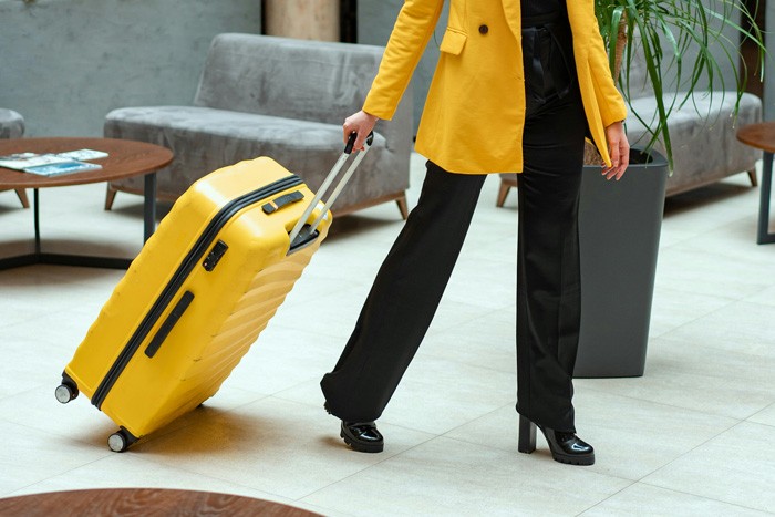 mujer de amarillo con maleta en el aeropuerto