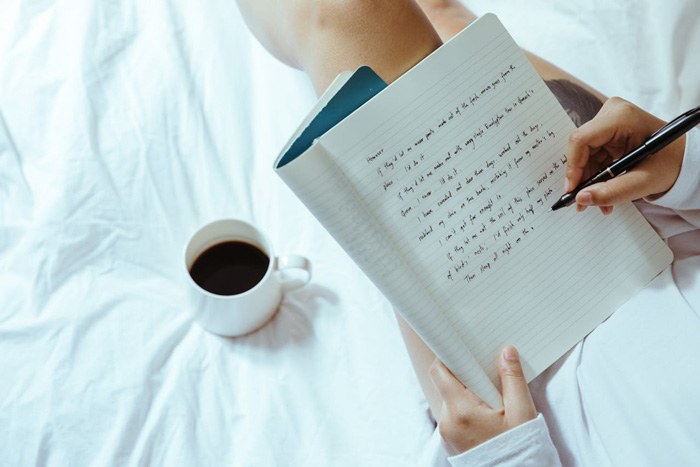 persona con cuaderno tomando apuntes notas y café