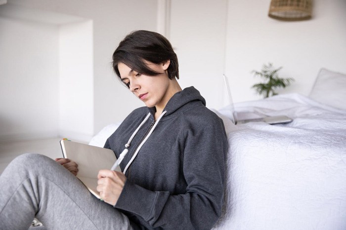 mujer estudiando con un cuaderno en el sofá