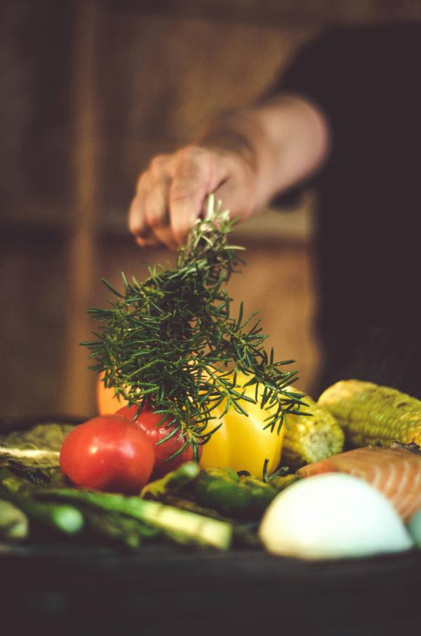 persona utilizando romero para cocinar