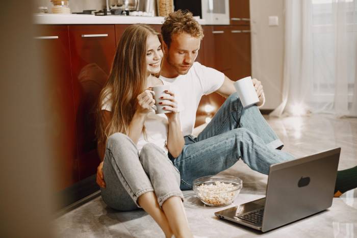 pareja con palomitas y tazas viendo serie en ordenador