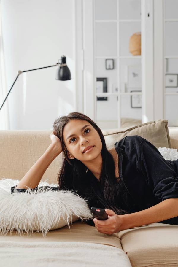 mujer chica joven viendo la tele en el sofa con mando